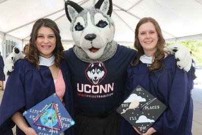 Neag School master's grads from the Class of 2019 celebrate with Jonathan the Husky mascot at the Student Union.