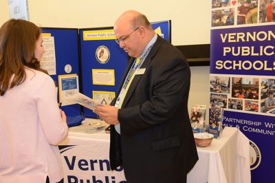 Joseph Macary ’94 (ED), ’08 ELP, ’16 Ed.D, superintendent of Vernon Public Schools, speaks with a student during the Education Career Fair. 