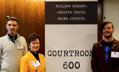 Three individuals stand in front of Courtroom 600 banner.