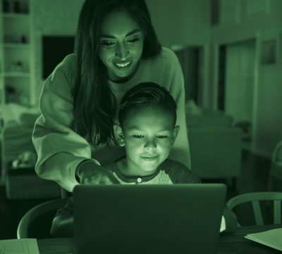 Parent overseeing child while looking at laptop,