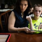 A 13-year-old boy with autism, uses a keyboard and iPad to communicate with his mother.