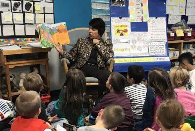 Principal Rodriguez reading a picture book to elementary school students.