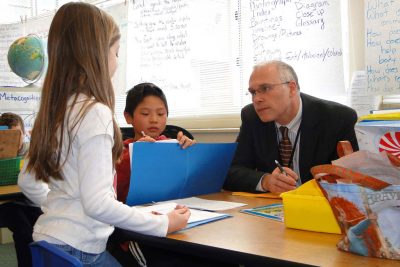 Superintendent Paul Freeman listens to child read in classroom.