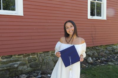 Isabella Gradante holds graduation cap in front of UConn's Red Barn.