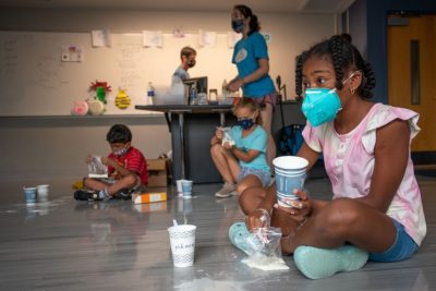 School age girl wearing mask interacts with science experiment during BRAIN Camp.