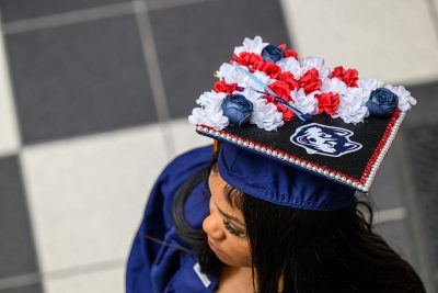 A graduate is seen from above with a decorated mortarboard. [Links to Commencement webpage]