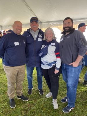 Four adults at UConn Homecoming event.