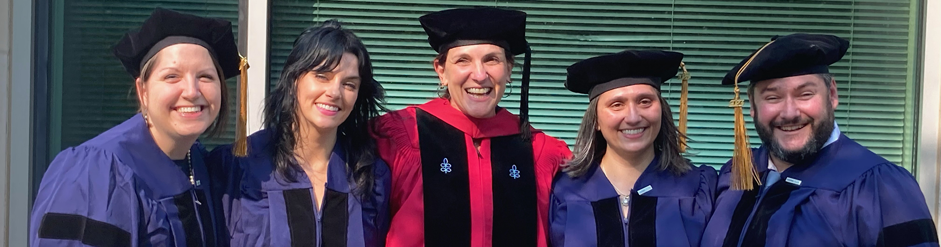 Five people in doctorate robes pose for a picture