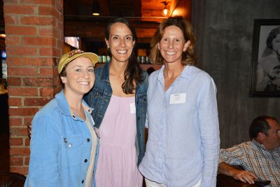 Three female smiling professionals gather at an event.
