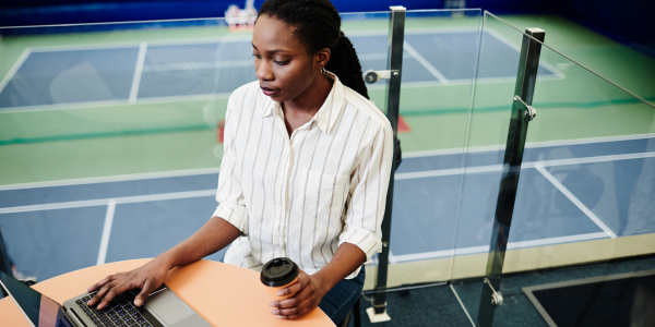 A woman works in an office overlooking tennis courts