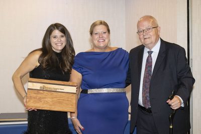 Three smiling professionals hold award.