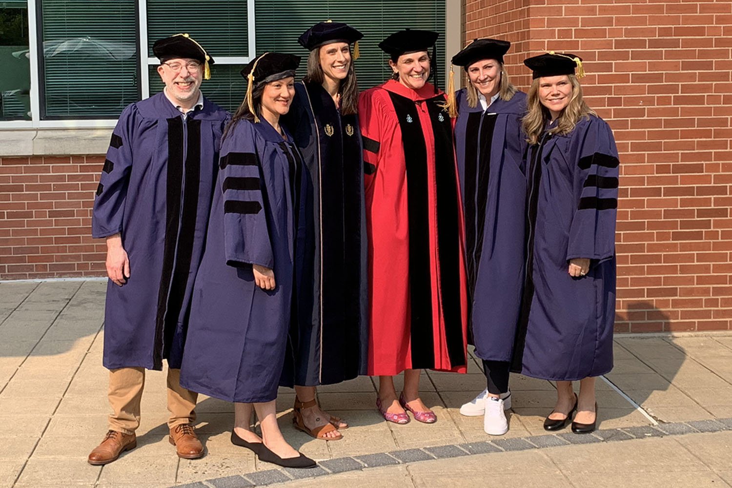 Five doctoral graduates and a faculty member pose outside the Gentry Building. [Links to doctoral programs webpage.]