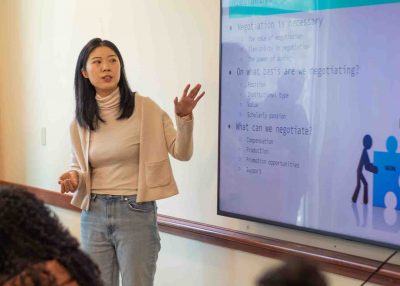 Asain woman stands in front of a smart board.