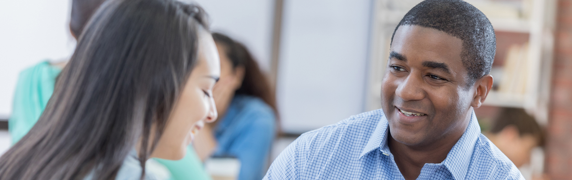 Mid adult African American school counselor talks with female student in the student lounge.