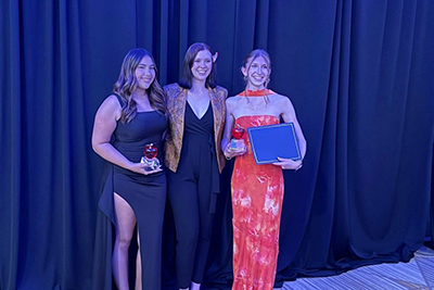 Three female professionals at an award ceremony.