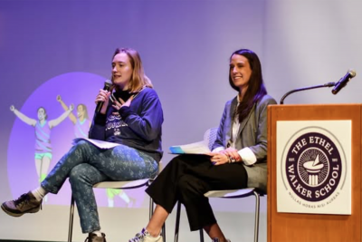 Two professional females on a stage speaking.