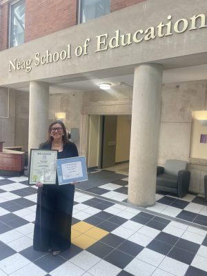 Tracy Sinclair holds an award while standing in the Gentry Building atrium.