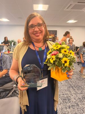 Claudia Bouchard holds an award and flowers.